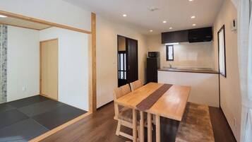A compact living space with a dining area, kitchenette, and a sliding door leading to a sleeping area.