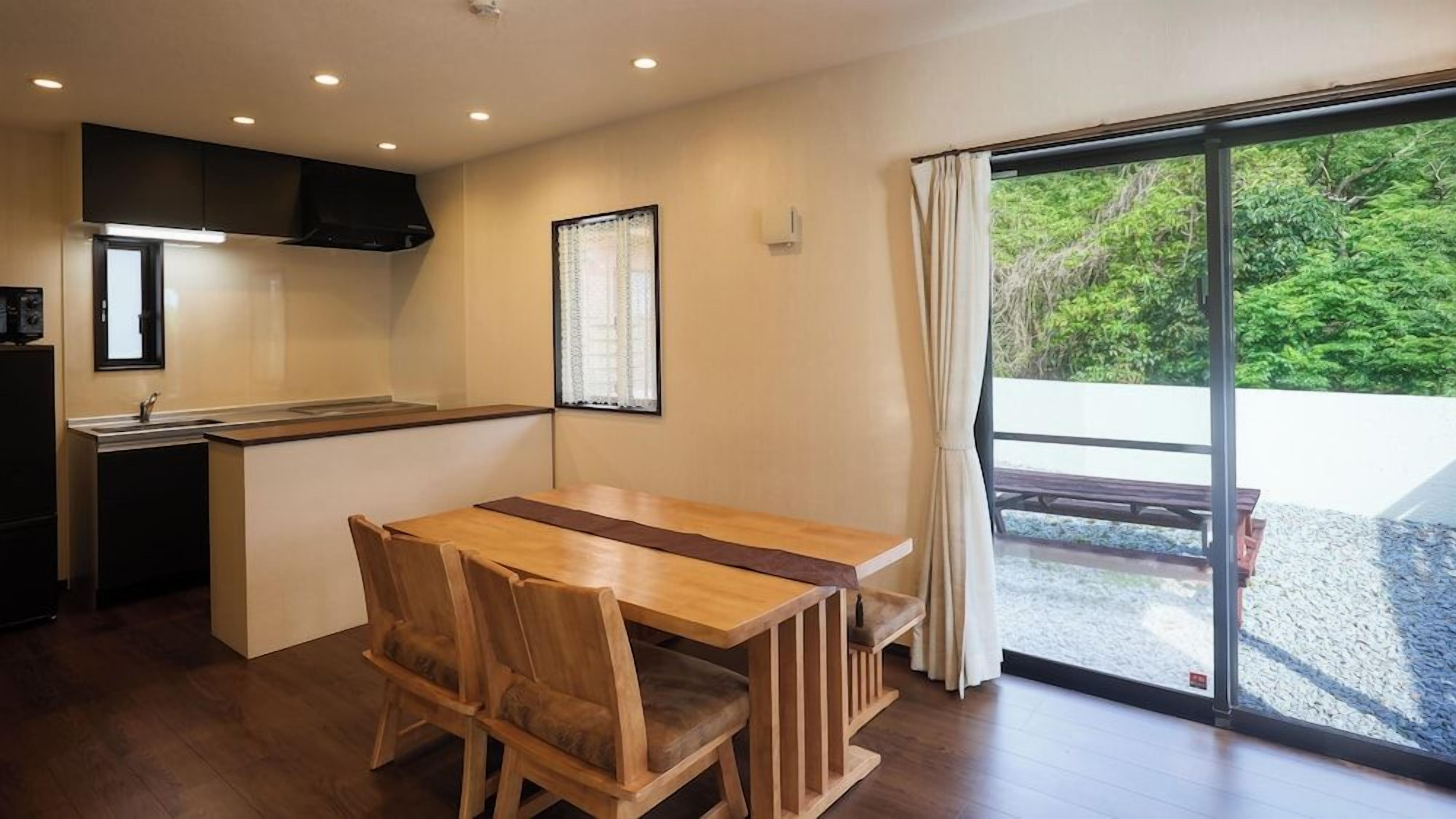 Una cocina moderna con comedor, un amplio ventanal con cortinas y vistas al exterior.