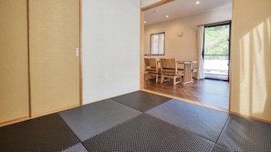 A room with tatami mats, a wooden table with chairs, and a sliding door. - Canopus Motobu [vr] (Motobu)
