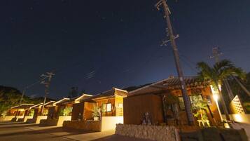 A row of traditional-style buildings with tiled roofs, a paved walkway, and a clear night sky.