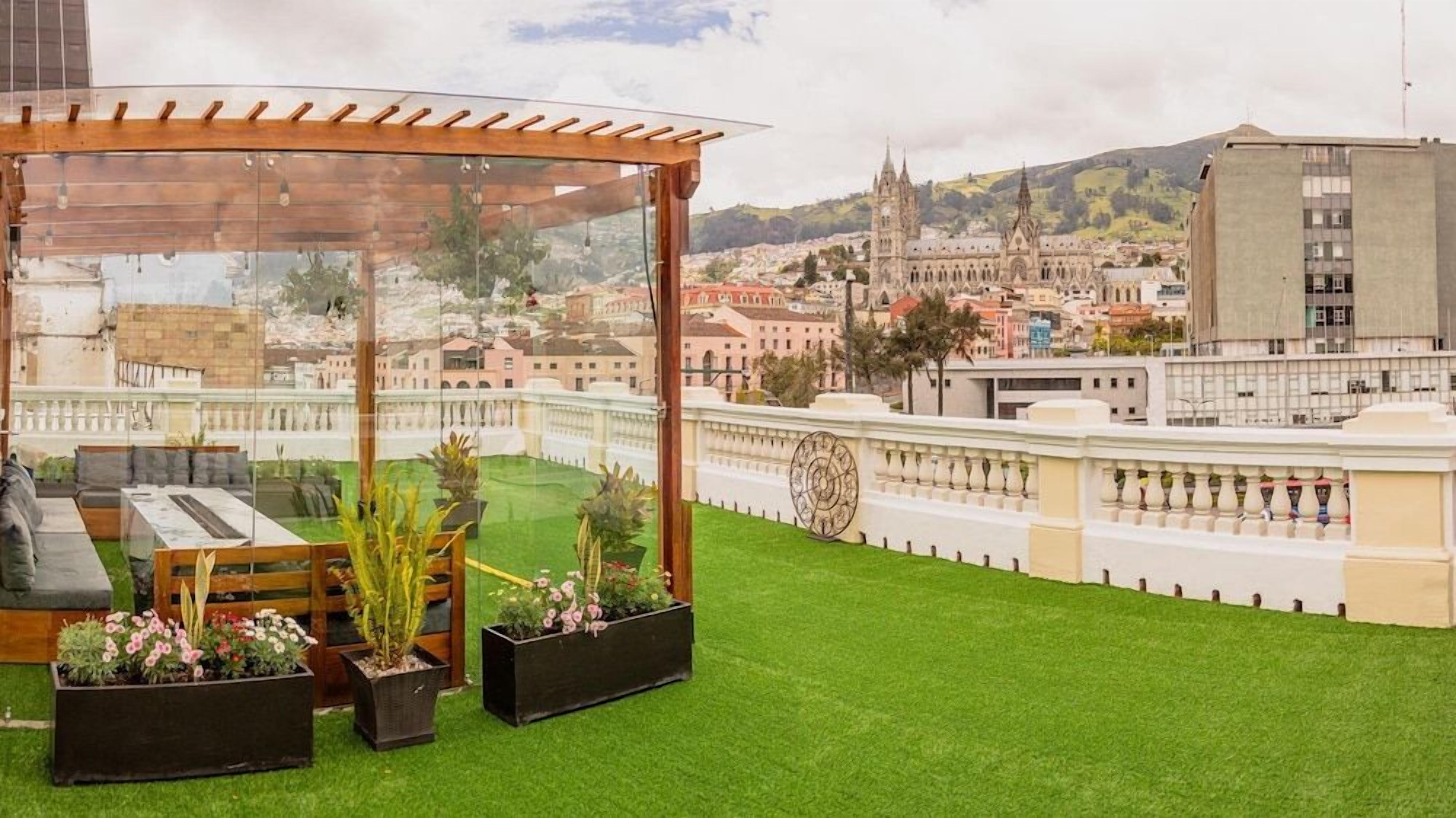 A rooftop terrace with a pergola, seating area, and potted plants.