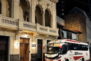 A historic building with ornate architecture, a vintage door, and a modern bus parked in front. - Hotel Boutique Casona D'alameda (Quito)