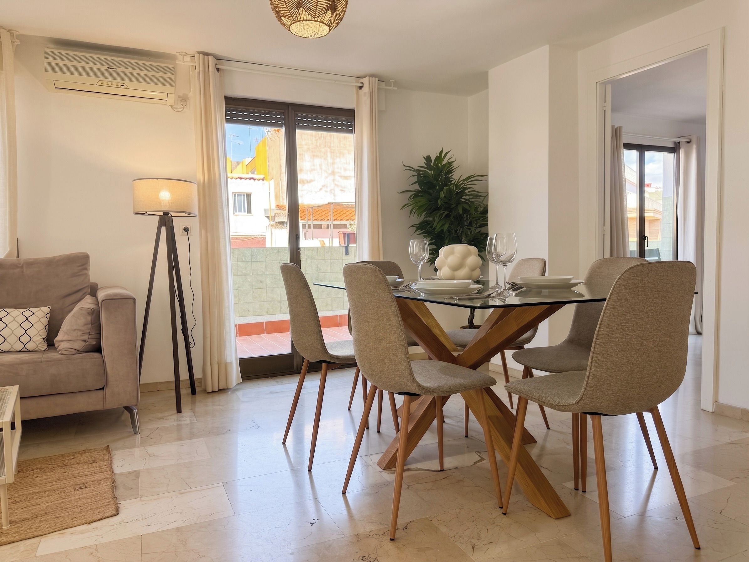 Un'area pranzo con un tavolo in vetro, quattro sedie, una lampada da terra e un divano.