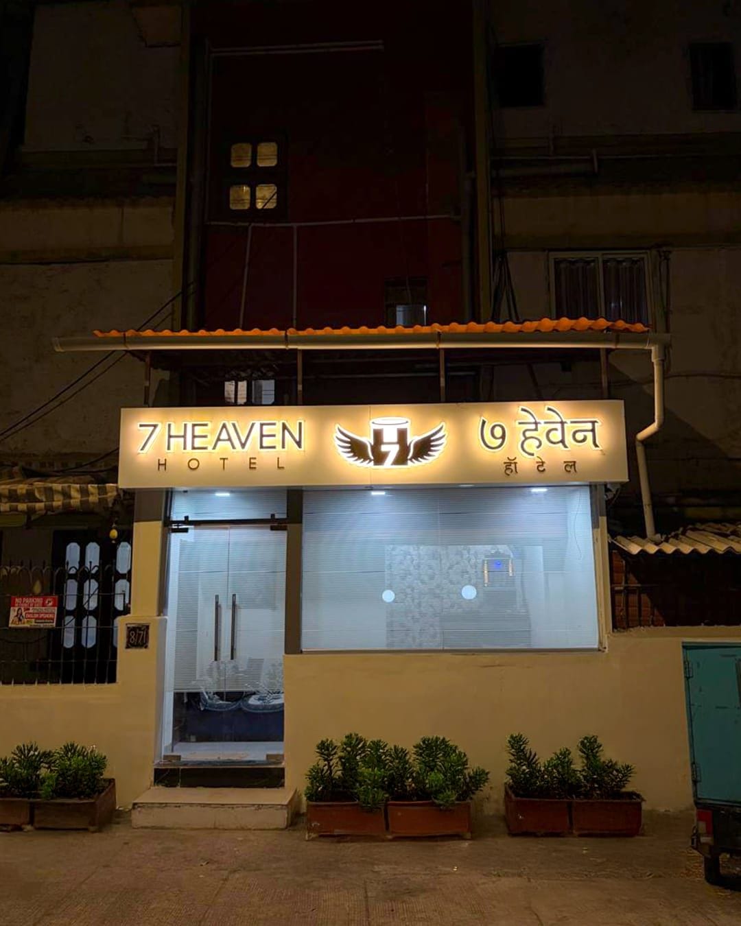 Um hotel chamado '7 Heaven' com uma placa em inglês e outro idioma.