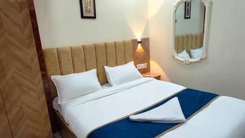 A hotel room with a bed, a nightstand, a wall-mounted mirror, and a framed picture.