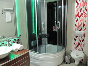 Un baño con ducha de vidrio, lavamanos blanco y un inodoro.