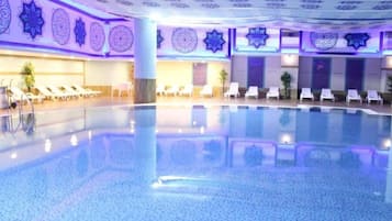 Ein großes Hallenbad mit Liegestühlen und dekorativen Wandmustern.