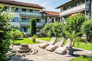 Un patio de hotel con suelo empedrado, sillones de descanso, una fuente y plantas en macetas.