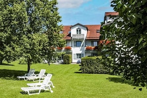 Ein Hotel mit gepflegter Rasenfläche, Sitzgelegenheiten im Freien und einem großen Gebäude mit rotem Dach.