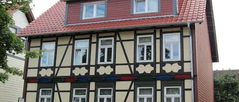 Un edificio tradicional con entramado de madera, múltiples ventanas y techo de tejas rojas.