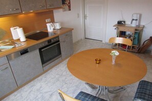 A compact kitchen with a dining table, chairs, a coffee maker, and a radio. - Holiday apartment with 1 bedroom (Wernigerode)