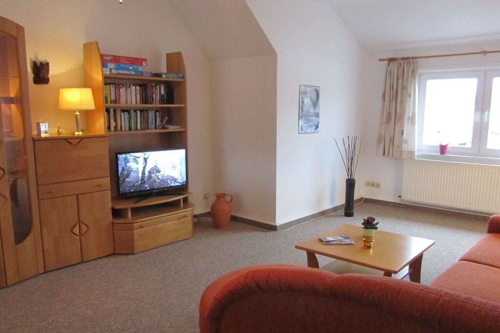 A living room with a television, a bookshelf, a coffee table, and a sofa.