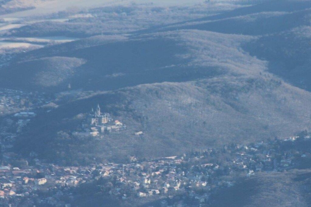 Uma vila aninhada em um vale, com uma construção imponente no topo de uma colina.