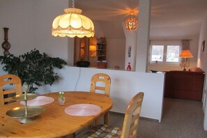 A dining area with a wooden table, chairs, a plant, and a chandelier. - Holiday apartment with 1 bedroom (Wernigerode)