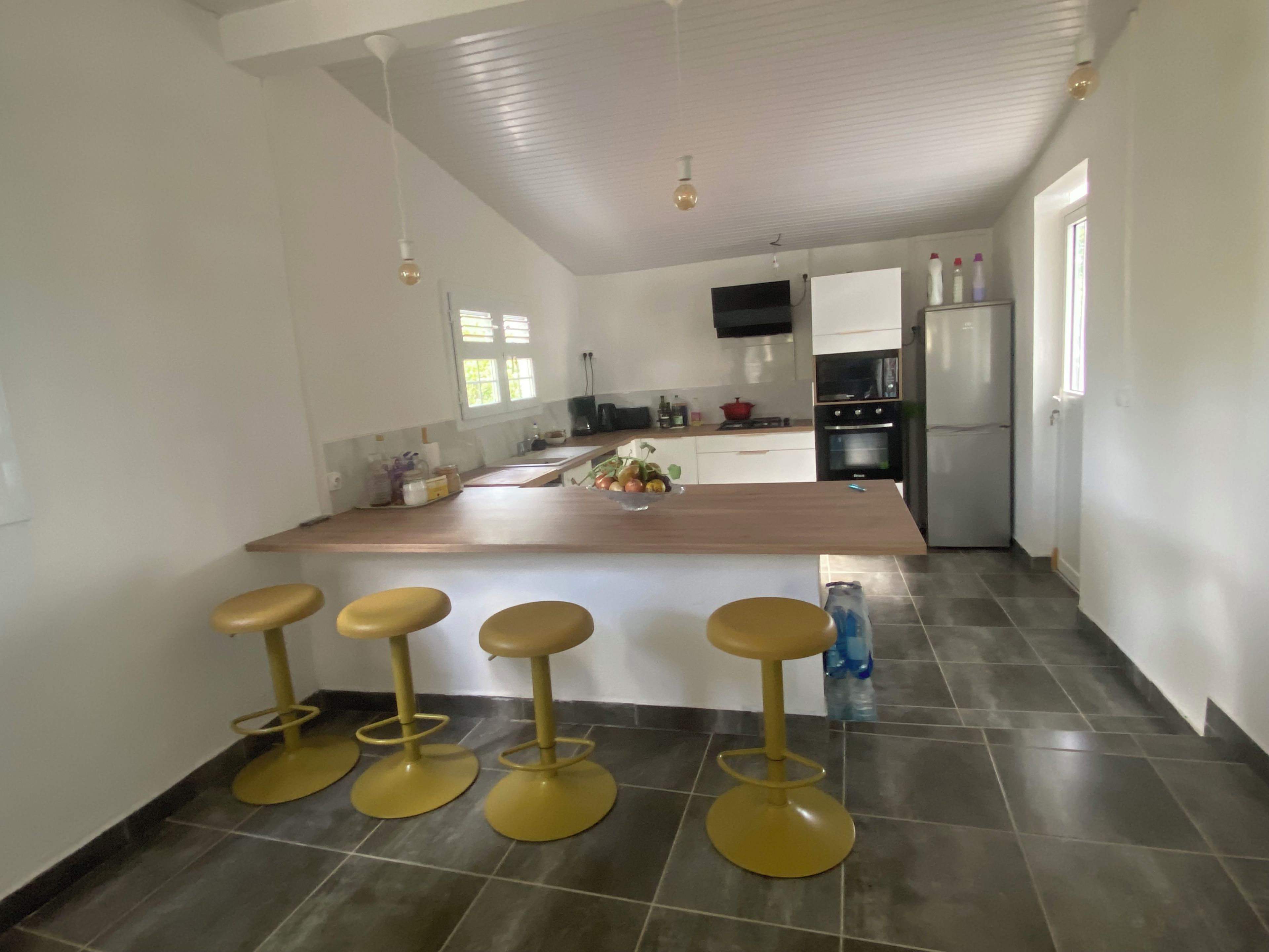 Une cuisine moderne dotée d’un îlot central, de tabourets de bar et d’un réfrigérateur.