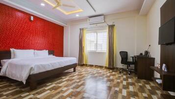 A hotel room with a bed, desk, chair, and a television.