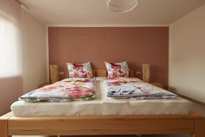 A bed with floral bedding, a wooden headboard, and two bedside lamps. - Pinot Noir at the Regnery winery (Klüsserath)
