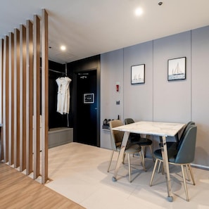 Une chambre d’hôtel moderne dotée d’un coin repas, d’une cloison en bois et d’un porte-manteau.
