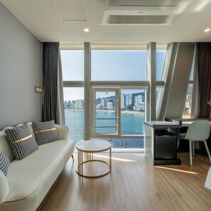 A modern living room with a sofa, a small round table, and a desk area. - Gwangalli Gray 193 Hotel (Busan)