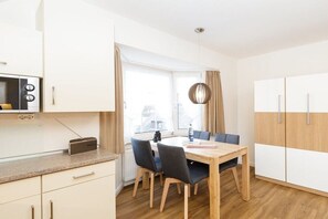 Eine moderne Küche mit Essbereich, einem Fenster mit Vorhängen und Blick auf die Stadt.