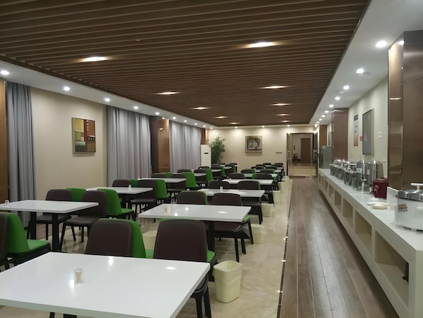 A spacious dining area with multiple tables and chairs, a long counter with a beverage station, and a modern ceiling design. - Greentree Inn Xuancheng Jingxian Wannan First Street Express Hotel (Xuancheng)
