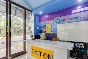 Oficina de agencia de viajes con mostrador de recepción, una pared con material promocional y una ventana con vistas al exterior.