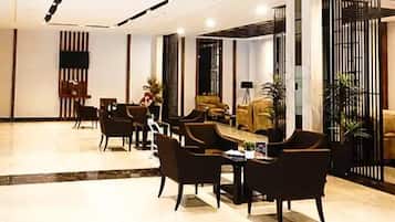 A hotel lobby with a reception desk, seating area, and a large screen.