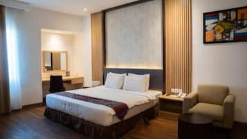 A hotel room with a large bed, a desk, a chair, and a small table.