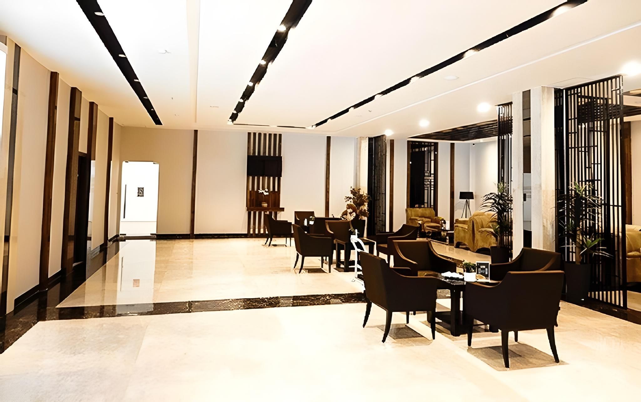 A modern hotel lobby with a reception desk, seating area, and a view of the lobby.