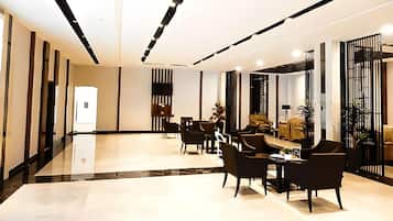 A modern hotel lobby with a reception desk, seating area, and a view of the lobby.