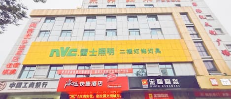 Un edificio de varios pisos con un llamativo letrero amarillo para un hotel y un restaurante.