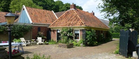 A courtyard with a brick building, outdoor seating, and a thatched-roof structure.