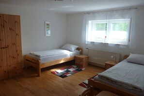 A bedroom with a single bed, a wooden wardrobe, a window with curtains, and a radiator. - Holiday apartment in Vöhl with swimming pool (Vöhl)