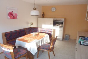 A dining area with a table set for four, a sofa, and a kitchen in the background. - Holiday apartment in Vöhl with swimming pool (Vöhl)