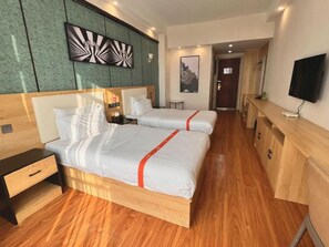 A hotel room with two beds, a TV, a desk, and a wooden cabinet.