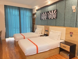 A hotel room with two beds, a wooden headboard, a nightstand, and a wall-mounted artwork.