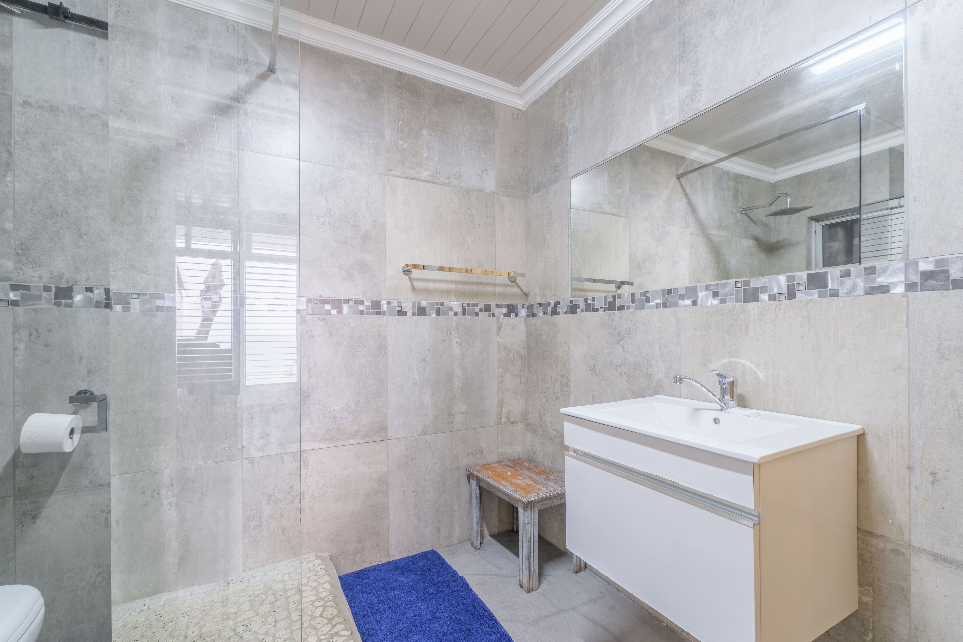 Une salle de bain équipée d’une douche, de toilettes, d’un lavabo et d’un miroir.