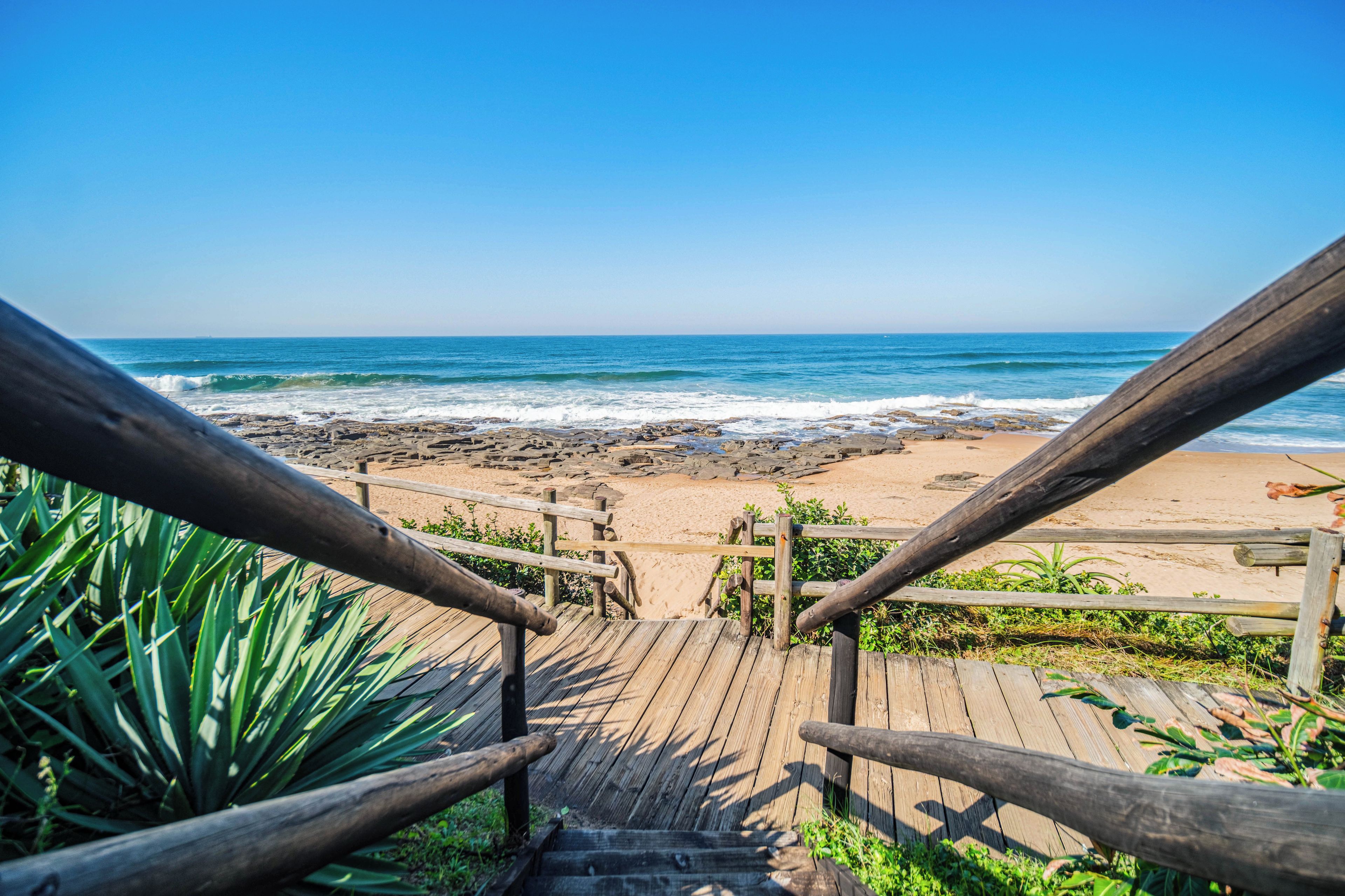 Eine Holztreppe führt zu einem Strand mit Blick auf das Meer.