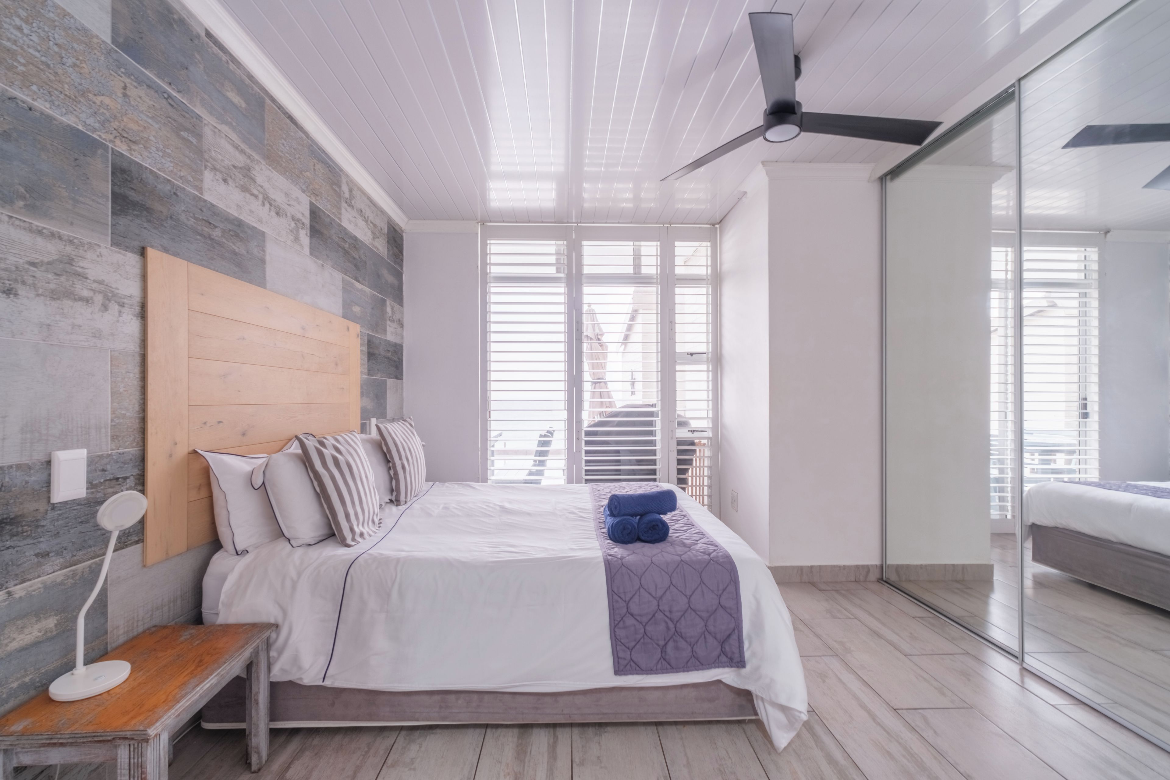 A modern bedroom with a bed, bedside table, and a view of the outside.