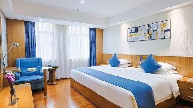 Una habitación de hotel con una cama grande, un escritorio, una silla y una mesita.