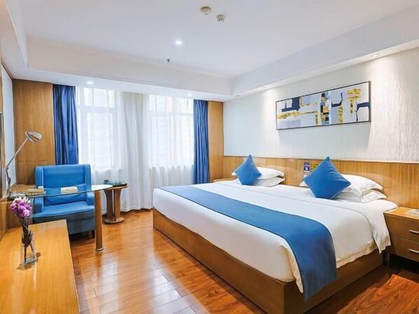 Una habitació d'hotel amb un llit gran, una taula de treball, una cadira i una taula petita.