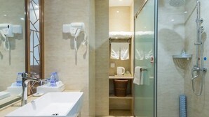 Un baño moderno con ducha de vidrio, lavamanos blanco y espejo.