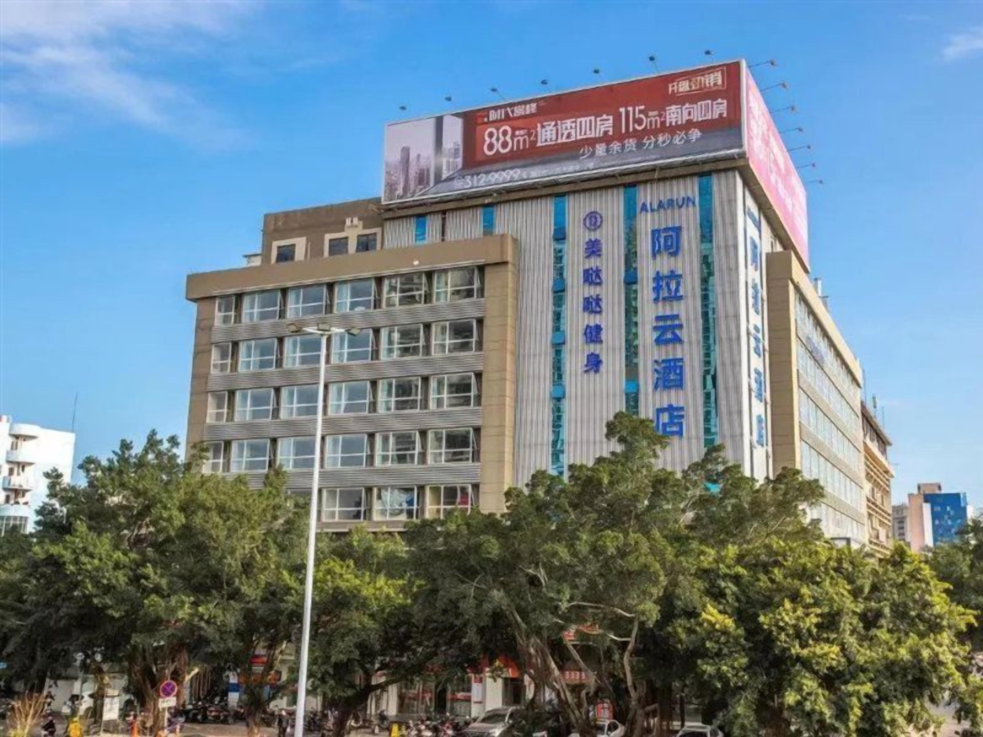 A multi-story hotel with a prominent billboard on the facade, multiple windows, and a visible entrance.