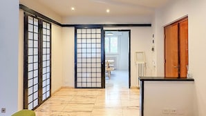 A spacious room with a tiled floor, a green sofa, a wooden cabinet, and a sliding glass door leading to another room. - Borgo Design Apartment by the sea (Civitavecchia)