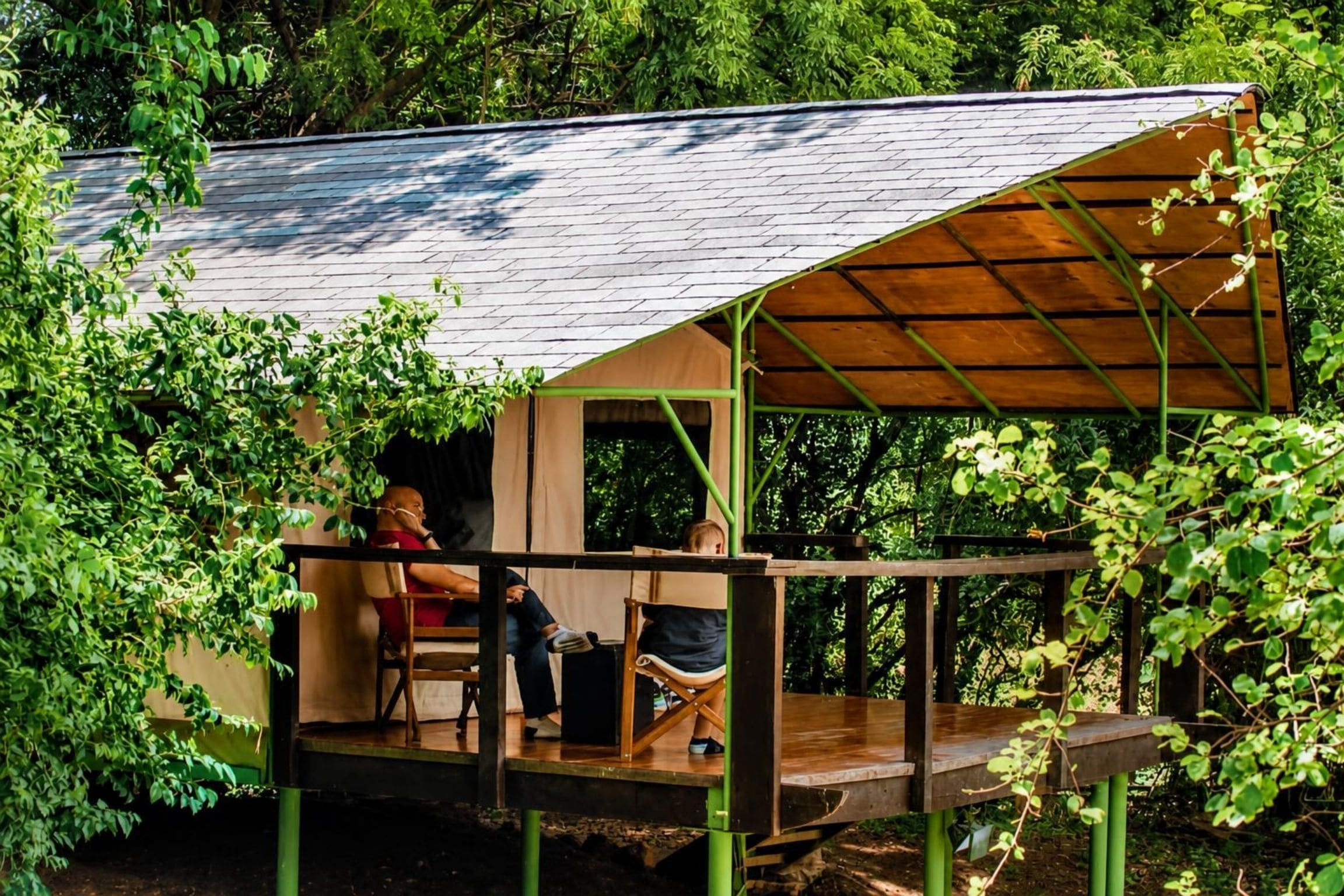 A wooden cabin with a covered deck and a view of the surrounding forest.