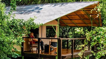 A wooden cabin with a covered deck and a view of the surrounding forest.
