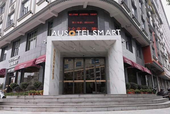 Entrada de un hotel con un cartel llamativo que dice 'AUSOTEL SMART' y una pantalla digital sobre la entrada.