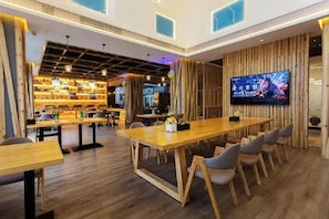 A modern interior with a long wooden table, chairs, and a television screen.