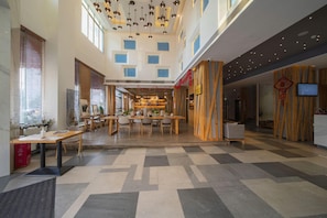 A spacious lobby with a high ceiling, multiple tables, and chairs arranged for seating.