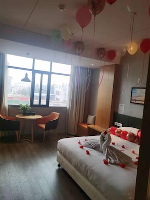 A hotel room with a bed, a seating area with chairs, a small table, and a window with curtains.